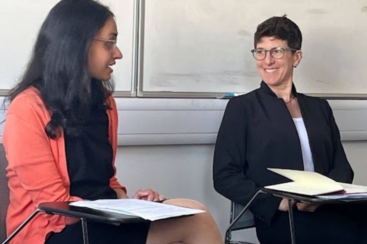 Julie Newman smiling as a fellow panellist beside her speaks, both holding notes
