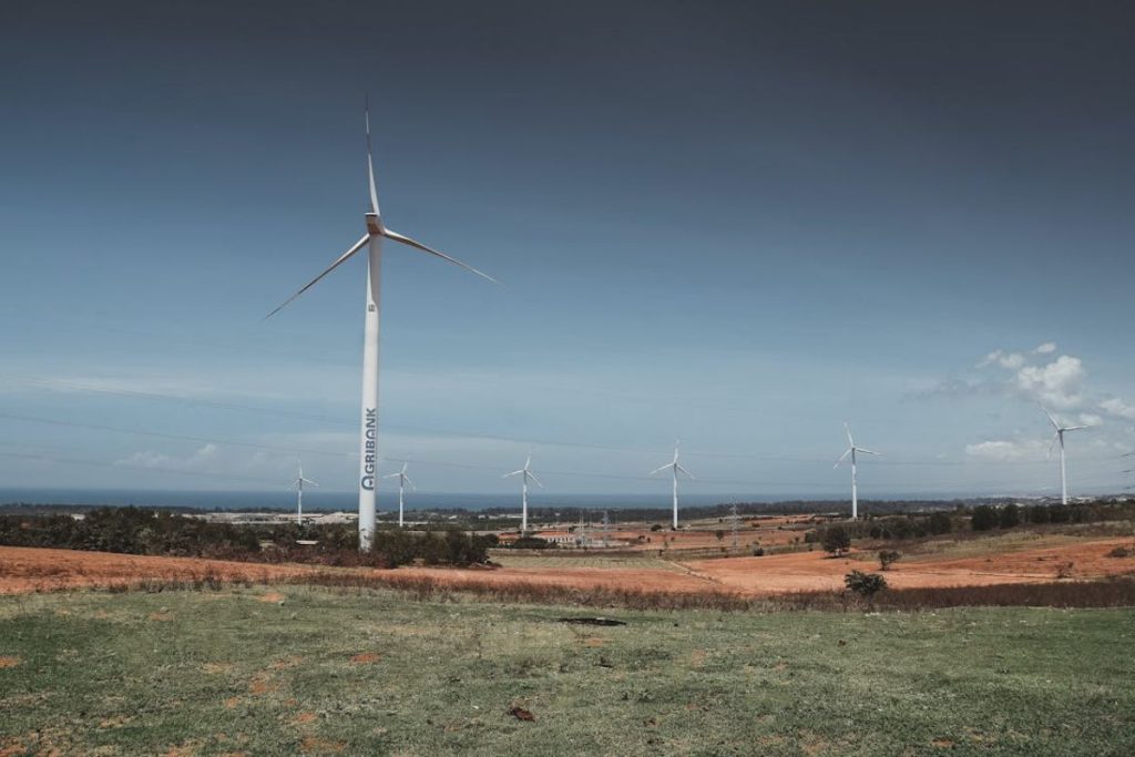 A wind farm in Southeast Asia, with turbines turning on a grassy hill, demonstrating large-scale renewable energy generation.