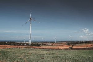 A wind farm in Southeast Asia, with turbines turning on a grassy hill, demonstrating large-scale renewable energy generation.
