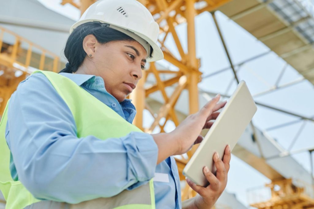 Female engineer using tablet at construction site, overseeing waste management for ESG sustainability project.