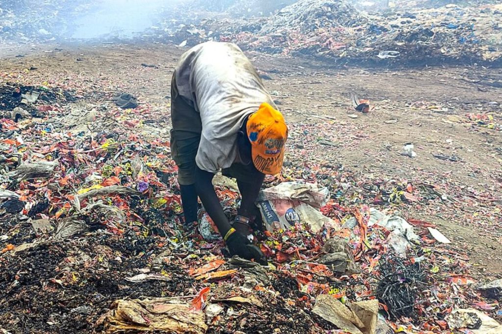 An informal waste picker sorts through plastic in a landfill, highlighting the human element of recycling supported by the ESG and CSR work of Earth5R, a waste management NGO in Mumbai.