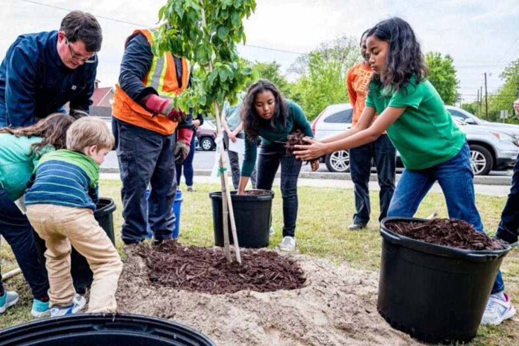 A diverse community group planting a tree together, an activity central to the mission of Earth5R Waste Management Sustainability NGO Mumbai ESG CSR.