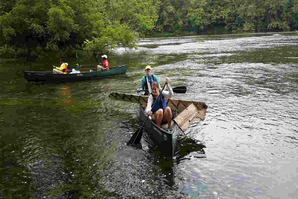 Tourists paddling through a river in canoes while collecting waste, highlighting eco-tourism initiatives that protect natural habitats and reflect Earth5R’s Sustainability, Waste Management, ESG, and CSR efforts as a leading NGO in Mumbai.