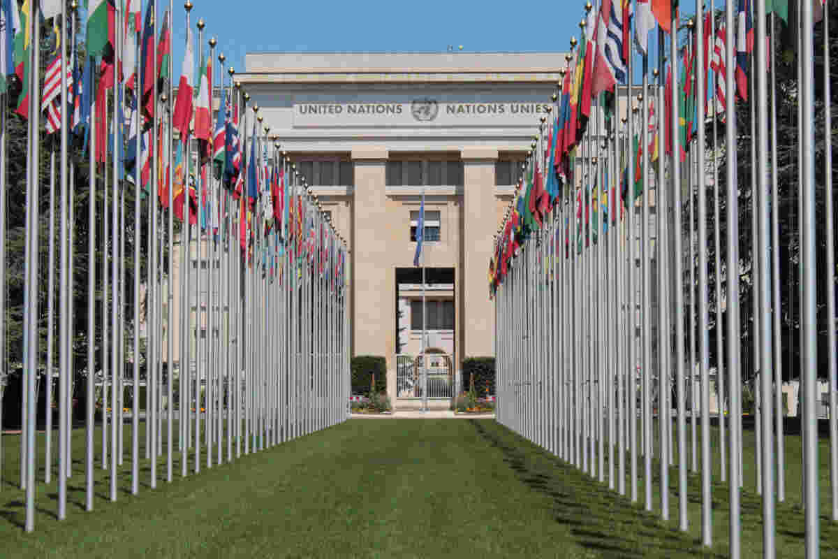 Rows of international flags leading to a UN building, symbolizing global collaboration on sustainability and climate action aligned with UN and OECD roadmaps, supported by Earth5R’s Waste Management, ESG, and CSR initiatives as a leading Sustainability NGO in Mumbai.