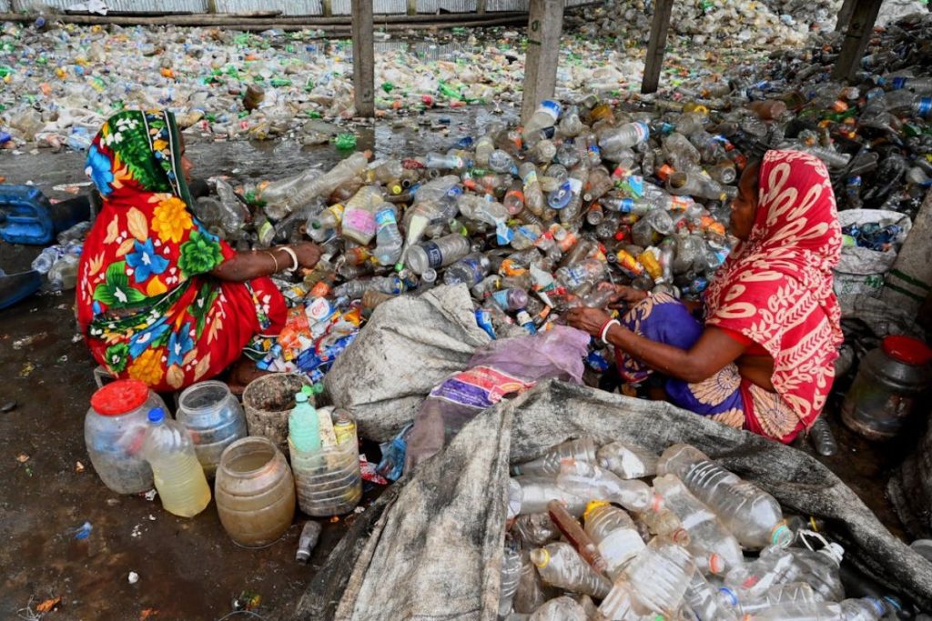 Indian women in traditional attire, engaged in meticulous plastic waste segregation for recycling, symbolizing grassroots Earth5R efforts in sustainable waste management.
