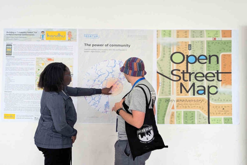 Two people discussing community mapping and sustainability insights while viewing posters related to OpenStreetMap, livability research, and social impact—reflecting themes of ESG, CSR, and NGO-led initiatives like those supported by Earth5R in Mumbai.