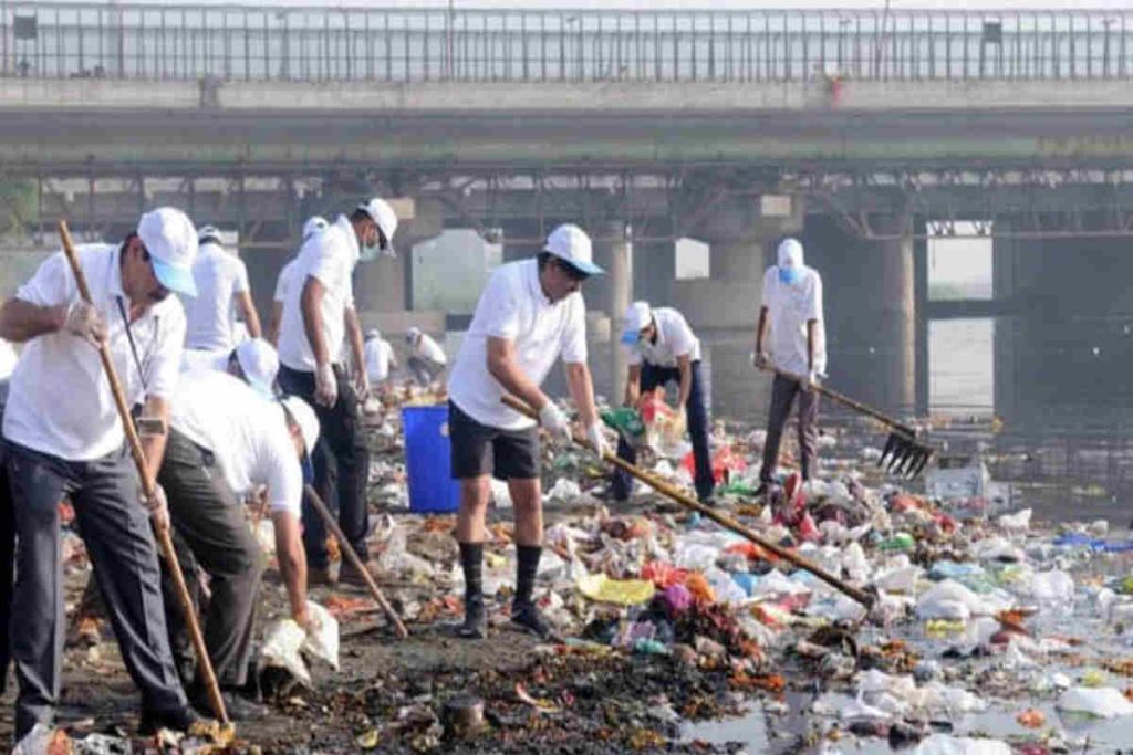 Volunteers in white uniforms participate in a large-scale shoreline cleanup in Mumbai, collecting plastic and waste as part of an NGO-led sustainability, CSR, and ESG-focused waste management initiative.