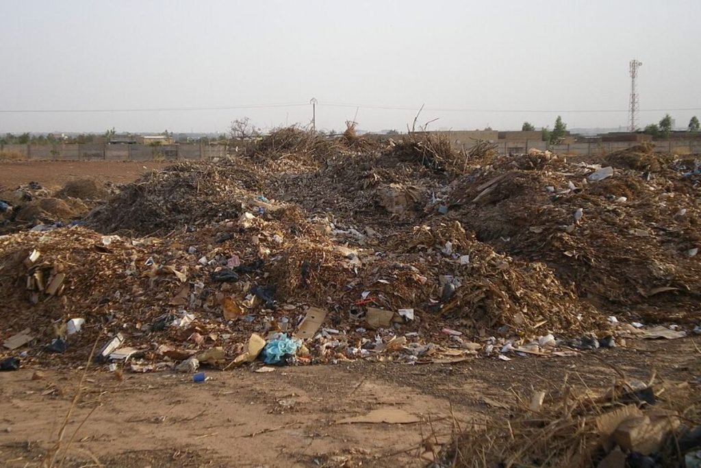 A large, sprawling pile of unsorted organic and municipal waste at a collection site, a source of methane emissions.
