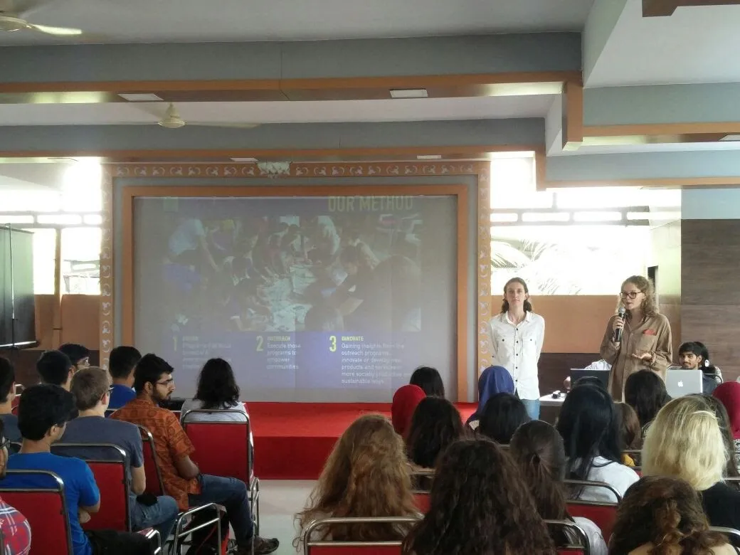 Presentation to international students in a hall, with slides on screen, Earth5R CSR programme