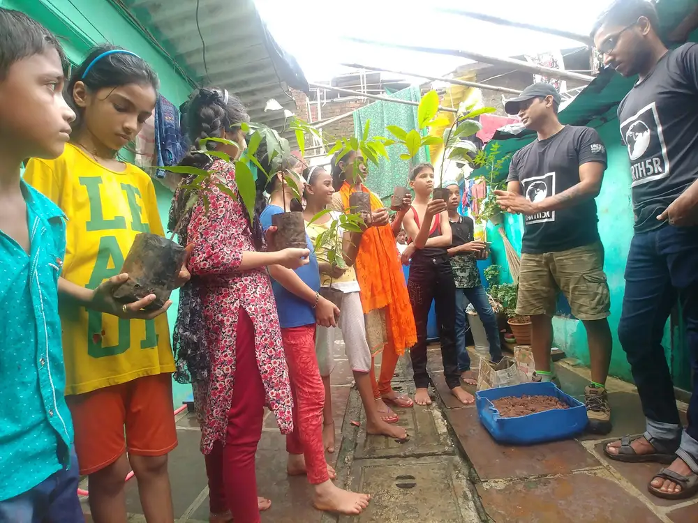 Children holding saplings for the Earth5R rooftop plantation programme in their settlement in Mumbai