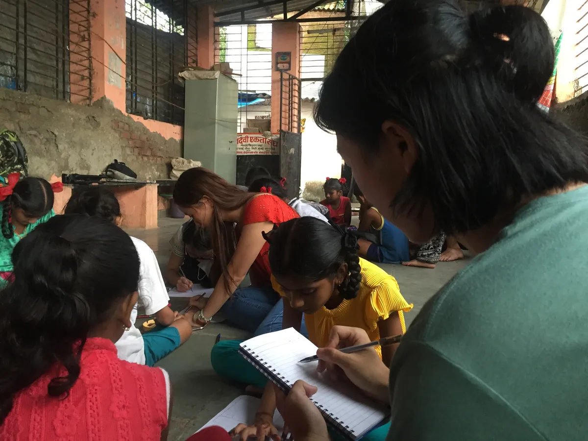 Children writing in notebooks with volunteers during a workshop, Earth5R CSR programme in Mumbai