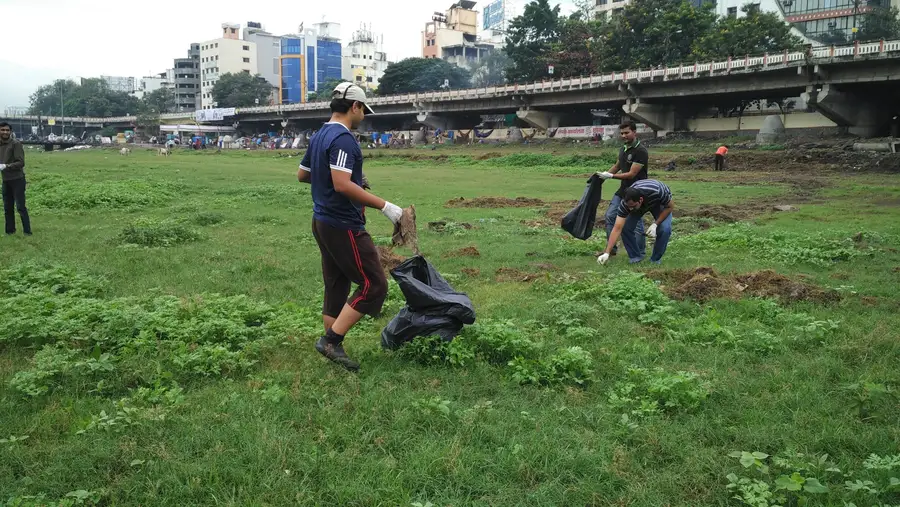Hexaware employee volunteers at an Earth5R corporate CSR cleanup on the Mula Mutha river in Pune