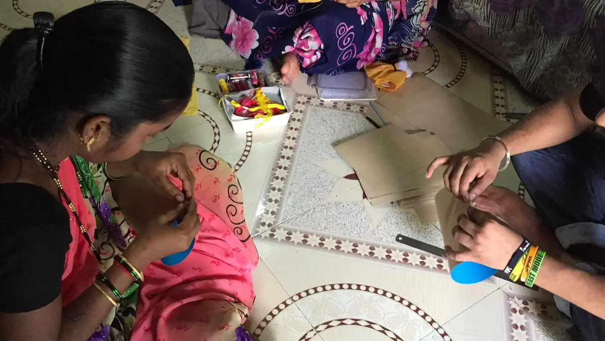 Hands folding and gluing paper to make bags, Earth5R CSR programme in Mumbai