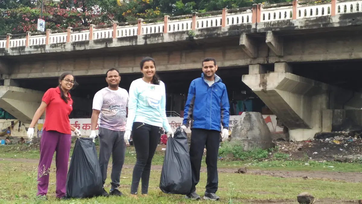 Hexaware employee volunteers with garbage bags at the Earth5R Mula Mutha river cleanup in Pune