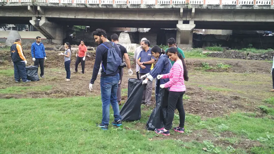 Hexaware employee volunteers bagging waste after Earth5R training at the Mula Mutha river cleanup in Pune