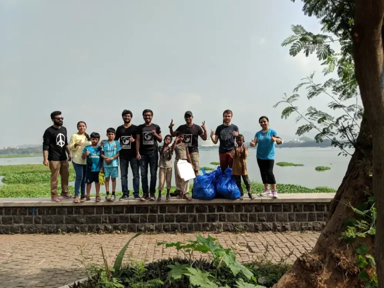 Families and children with bags of waste after an Earth5R cleanup at Powai Lake, Mumbai