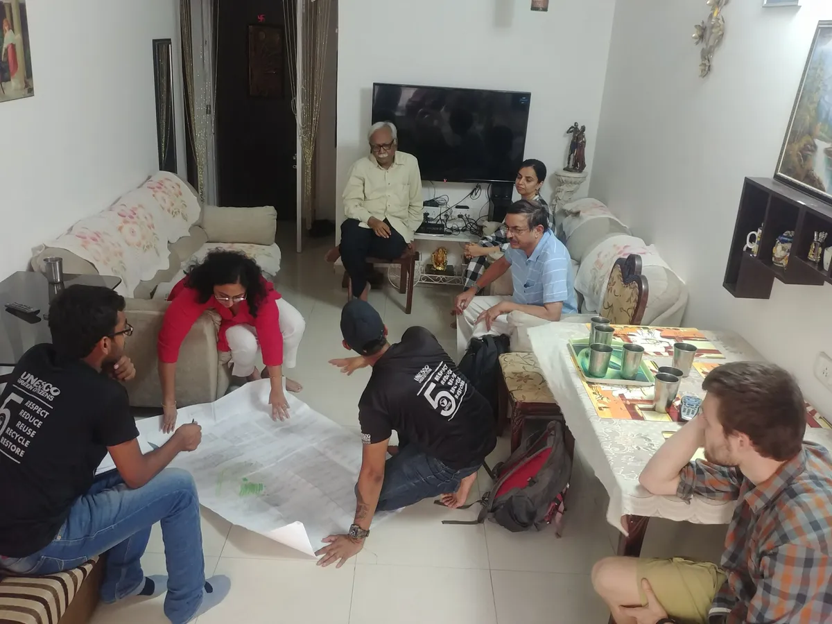 Urban planning internship field work. Earth5R team designing a local sustainability plan on chart paper with residents in their home in Mumbai