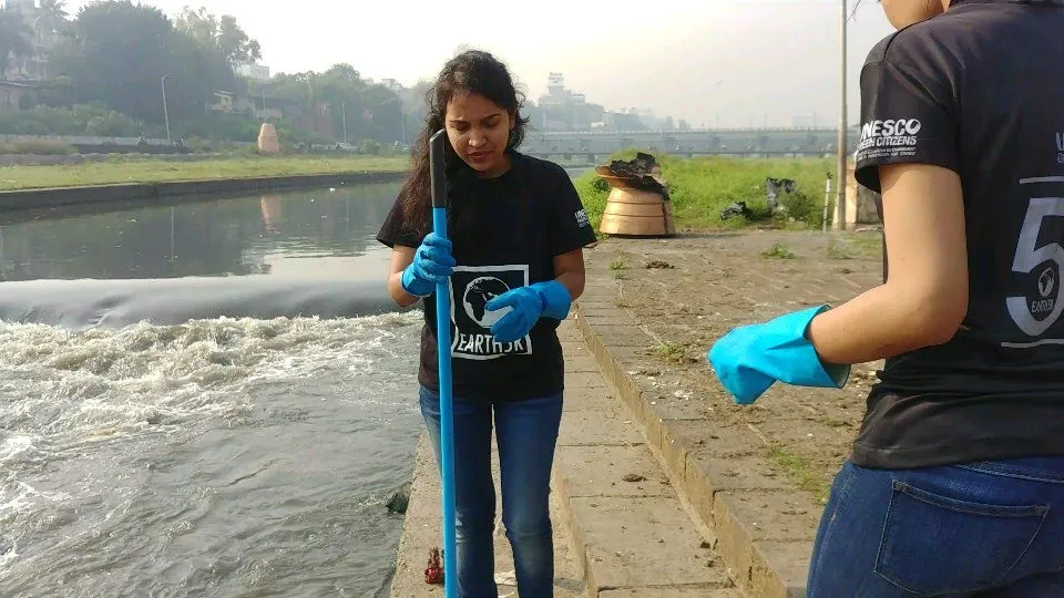 Earth5R volunteers with grabbers on the Mula Mutha riverbank during a cleanup in Pune