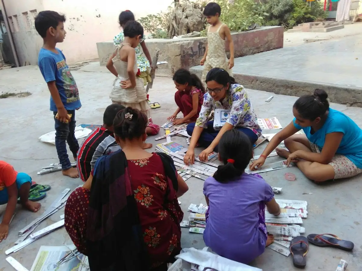 Children and volunteers rolling newspaper for an upcycling craft activity, Earth5R CSR programme