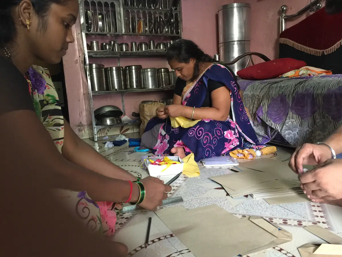 Earth5R volunteer training a woman to make paper bags in her home in Mumbai