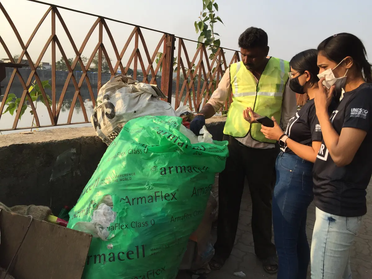 Earth5R team logging recovered plastic data with a waste collector at the Mithi River in Mumbai, ESG data for recycling and waste management