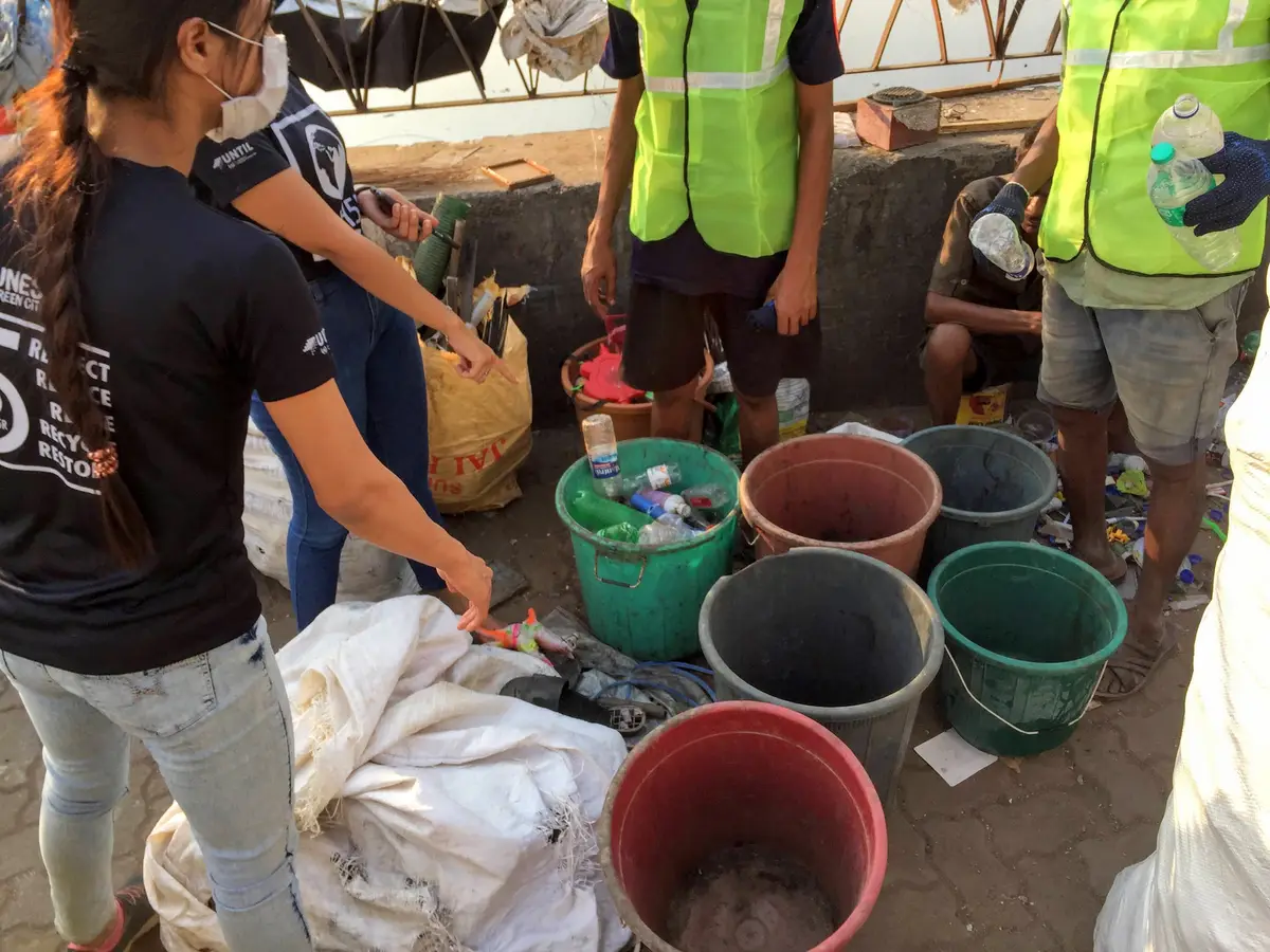Earth5R team and waste collectors sorting plastic into buckets by type near the Mithi River, Mumbai