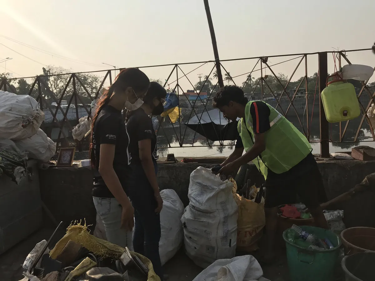 Earth5R trainers helping waste collectors sort plastic into sacks at the Mithi River in Mumbai