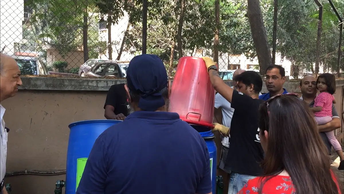 Biotechnology internship field work. Residents watching how the Earth5R drum composter is filled and rotated in Mumbai