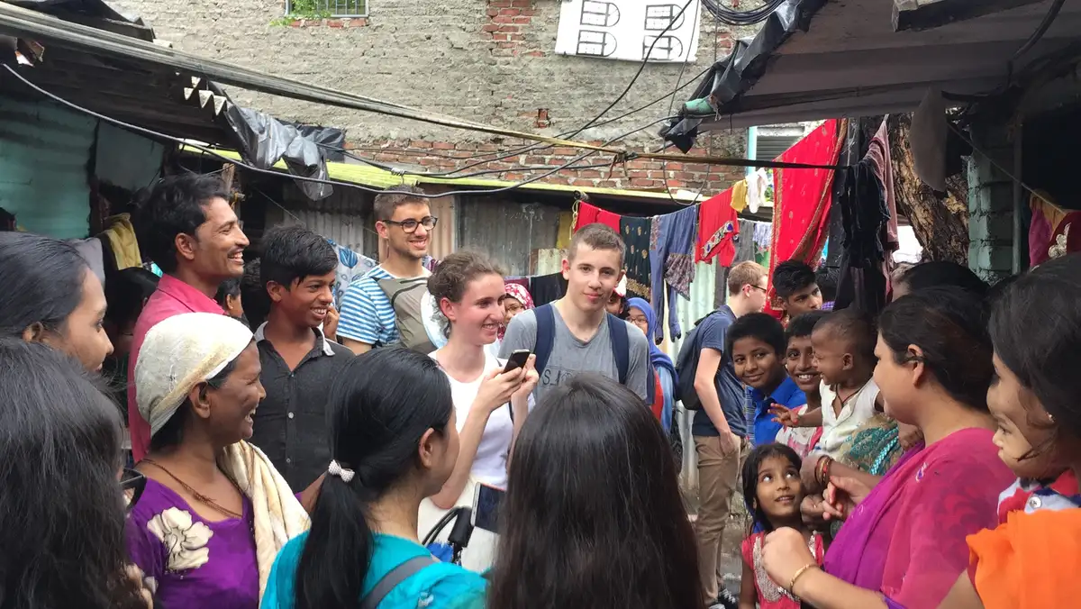 Residents and children gathered around visiting student volunteers in a settlement, Earth5R CSR programme in Mumbai