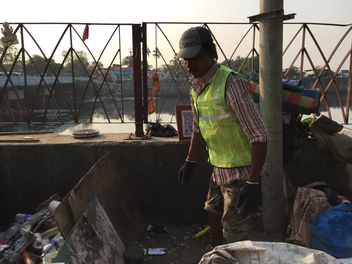 Waste collector in a safety vest recovering plastic waste along the Mithi River, Mumbai, Earth5R CSR programme