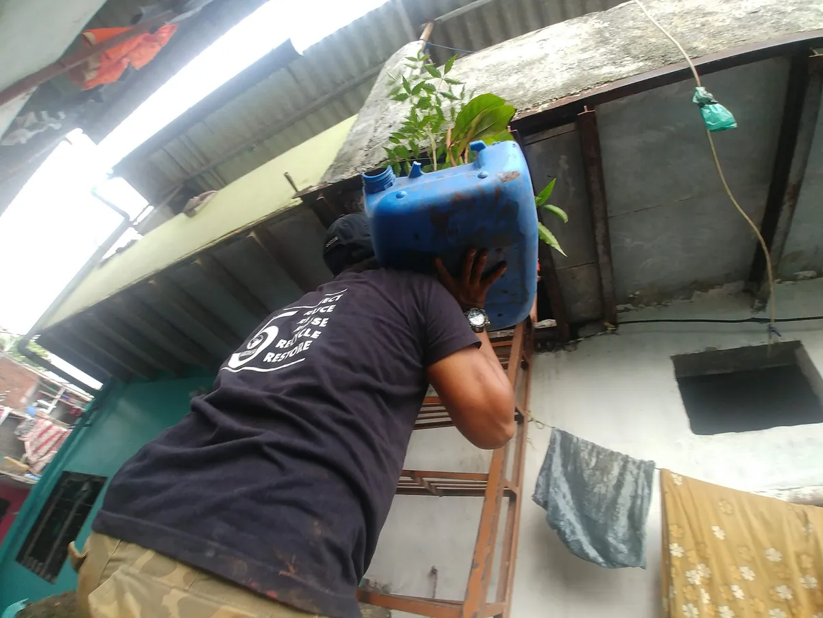 Earth5R volunteer placing a sapling planter on a hot tin roof to cool the home in Mumbai