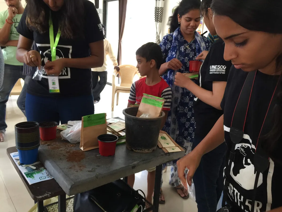 Earth5R volunteers Sonam Sengar, Shriyam Jalan, Manasi teaching children and parents to pot saplings with compost