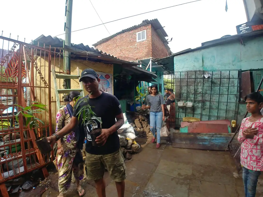 Earth5R volunteer carrying saplings into an informal settlement for the rooftop plantation programme in Mumbai
