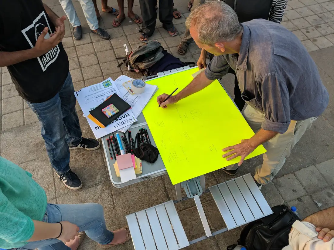 Climate change internship field work. Citizen writing a climate solution idea on a chart at an Earth5R street hackathon in Mumbai