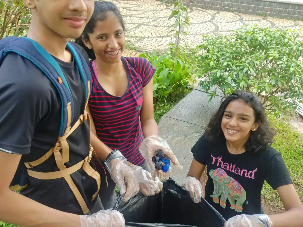 High school biology internship field work. Student volunteers collecting waste into bags at an Earth5R lake cleanup