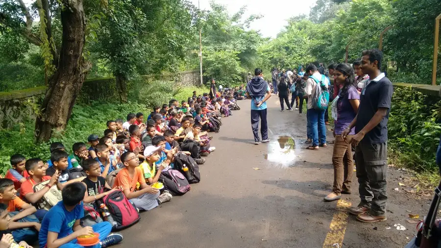 Large group of school students seated along a road during a cleanup drive, Earth5R CSR programme