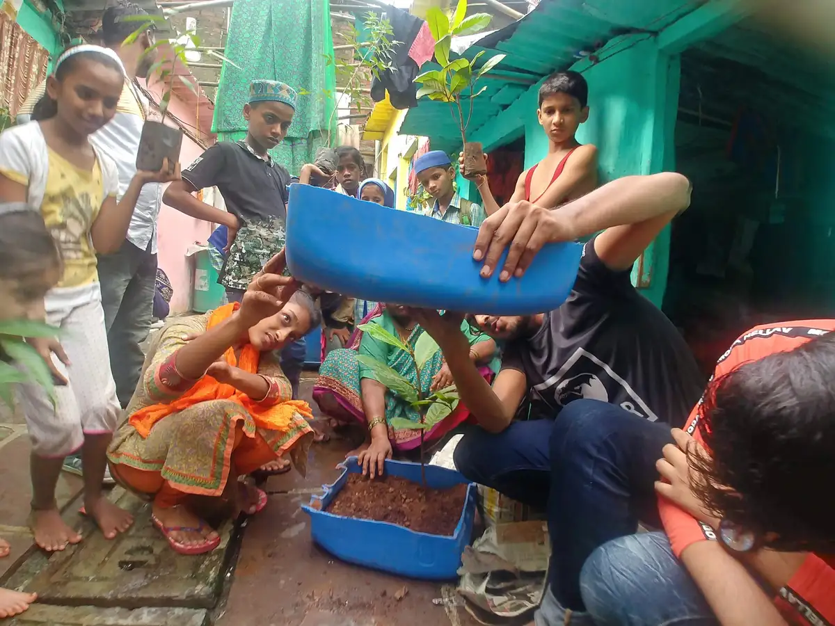 High school product design internship field work. Earth5R trainer showing women how to cut and drain upcycled plastic containers as planters in Mumbai