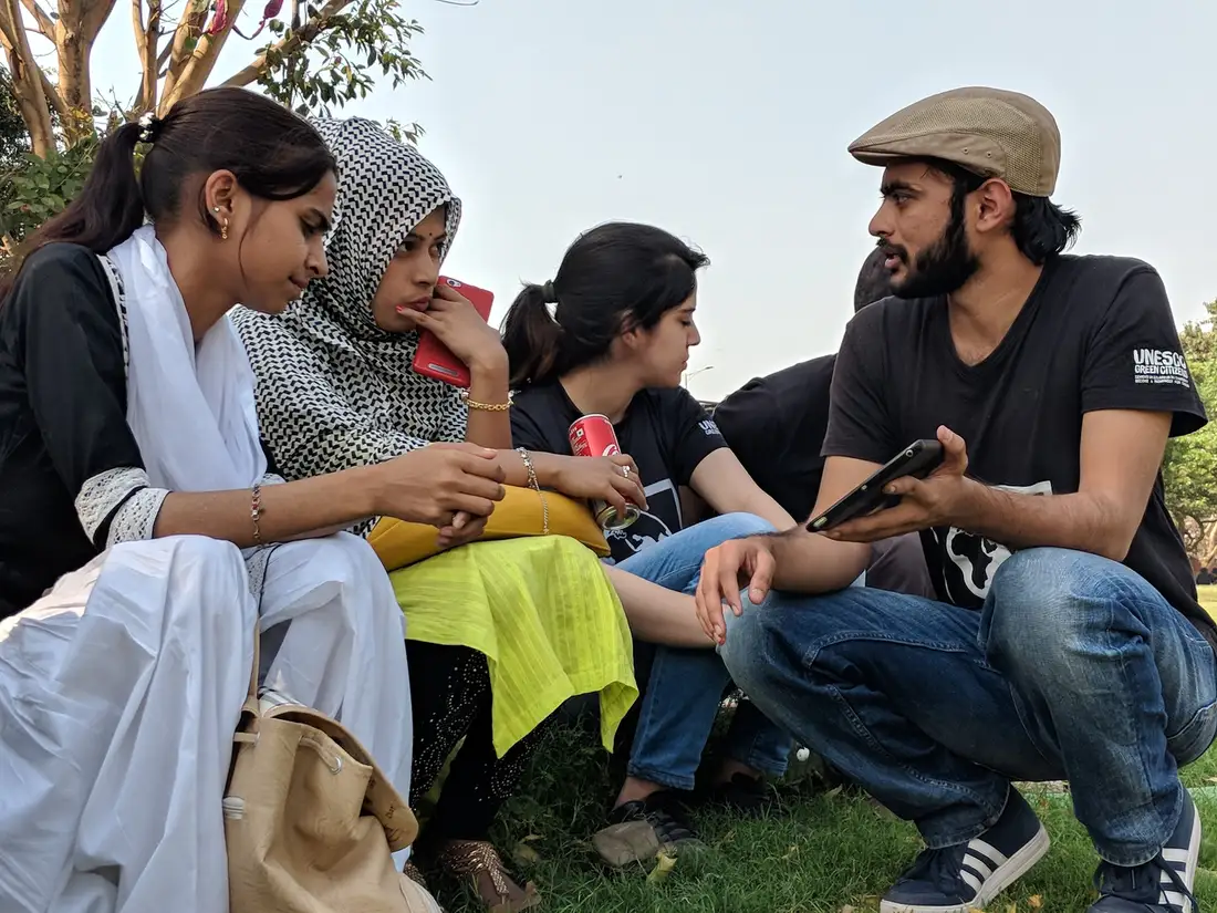 Earth5R volunteer showing women how to learn about circular economy on a phone in Delhi