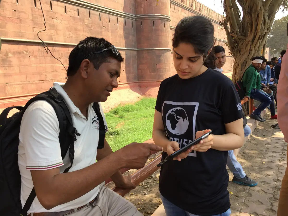 Earth5R volunteer explaining recycling to a citizen on a tablet near the Red Fort, Delhi