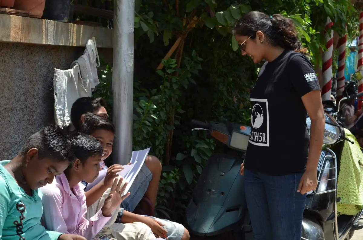 Earth5R volunteer guiding a group of boys working on environmental worksheets