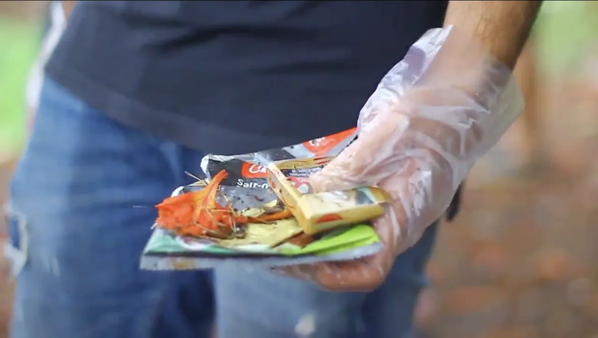Volunteer holding plastic wrappers recovered during an Earth5R lake cleanup
