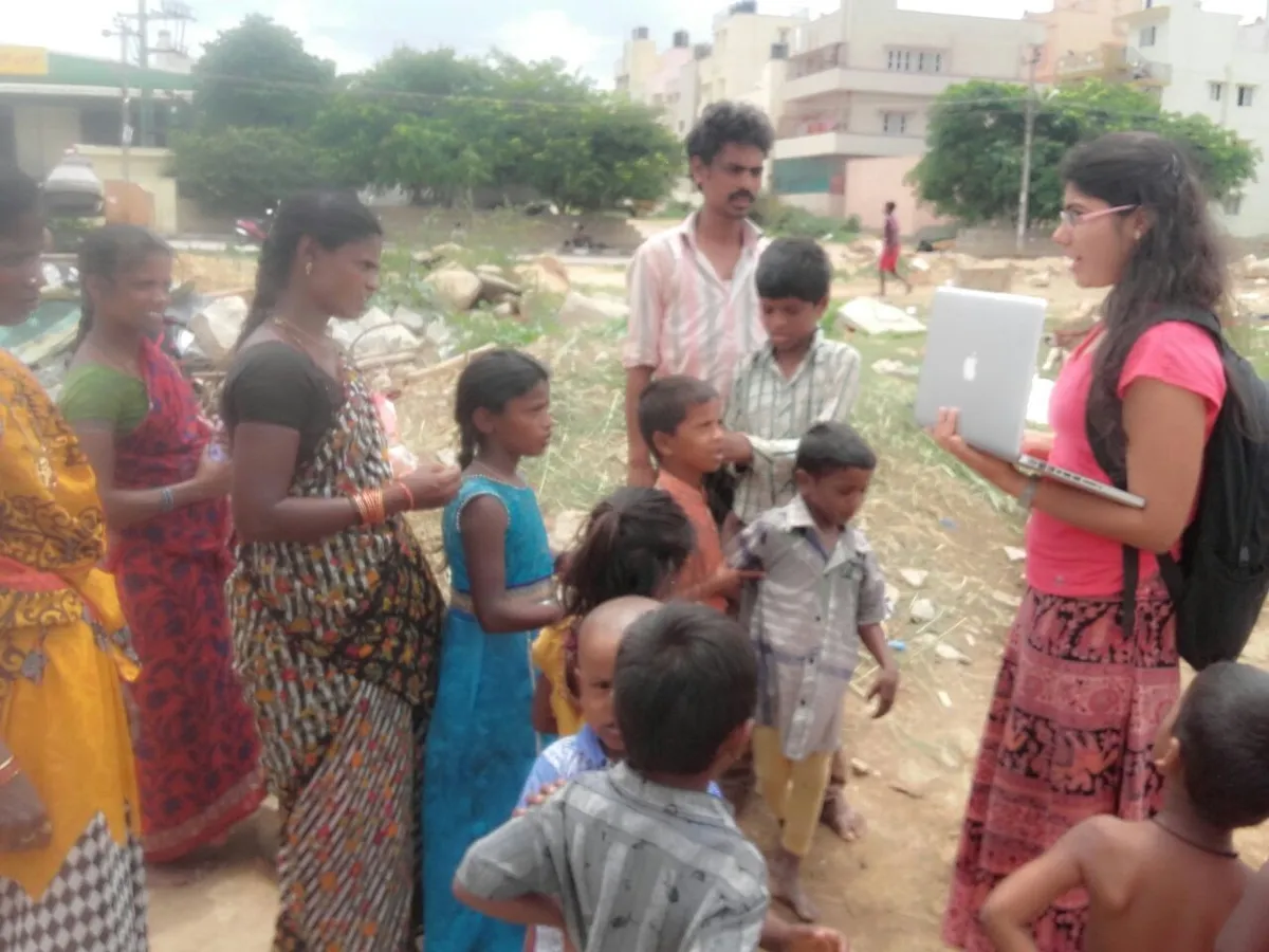 Earth5R volunteer with a laptop talking to residents and children during a community survey