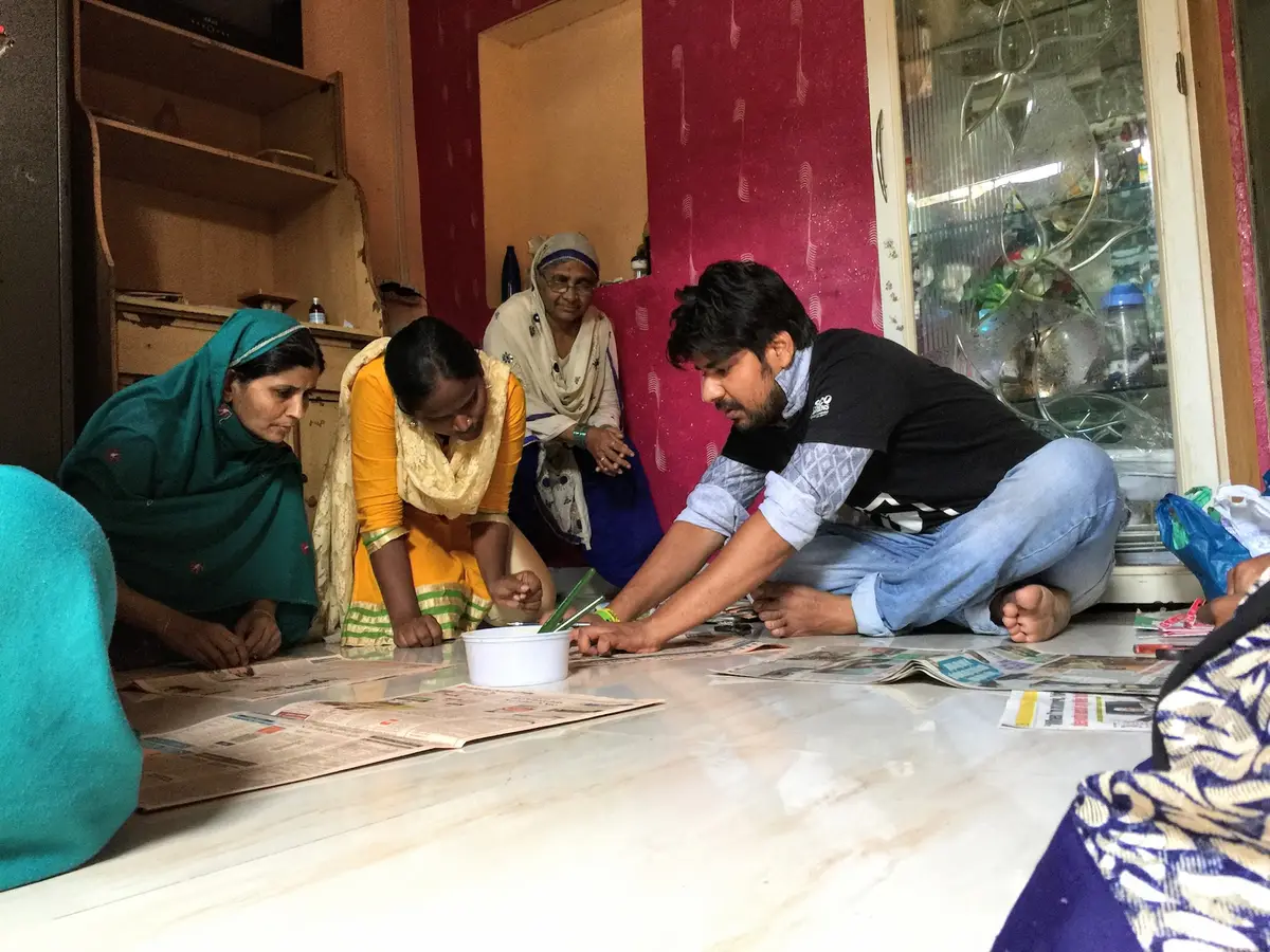 Earth5R volunteer teaching women the paper bag folding technique
