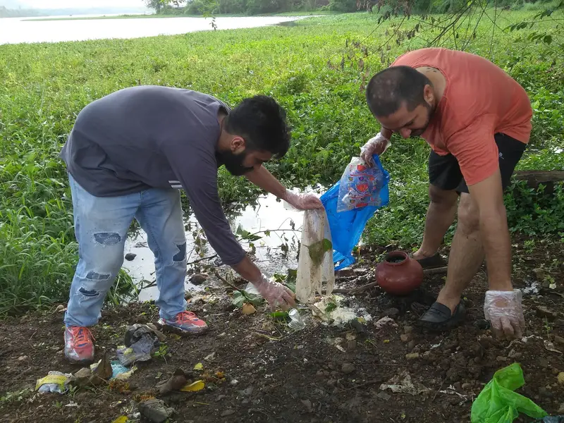Earth5R volunteers clearing mixed waste and an offering pot from the Powai Lake shore, Mumbai
