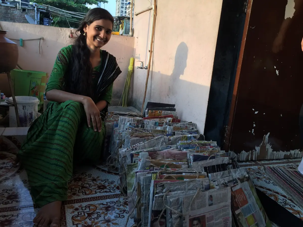 Woman with stacks of finished newspaper paper bags ready for sale to local shops, Earth5R CSR programme