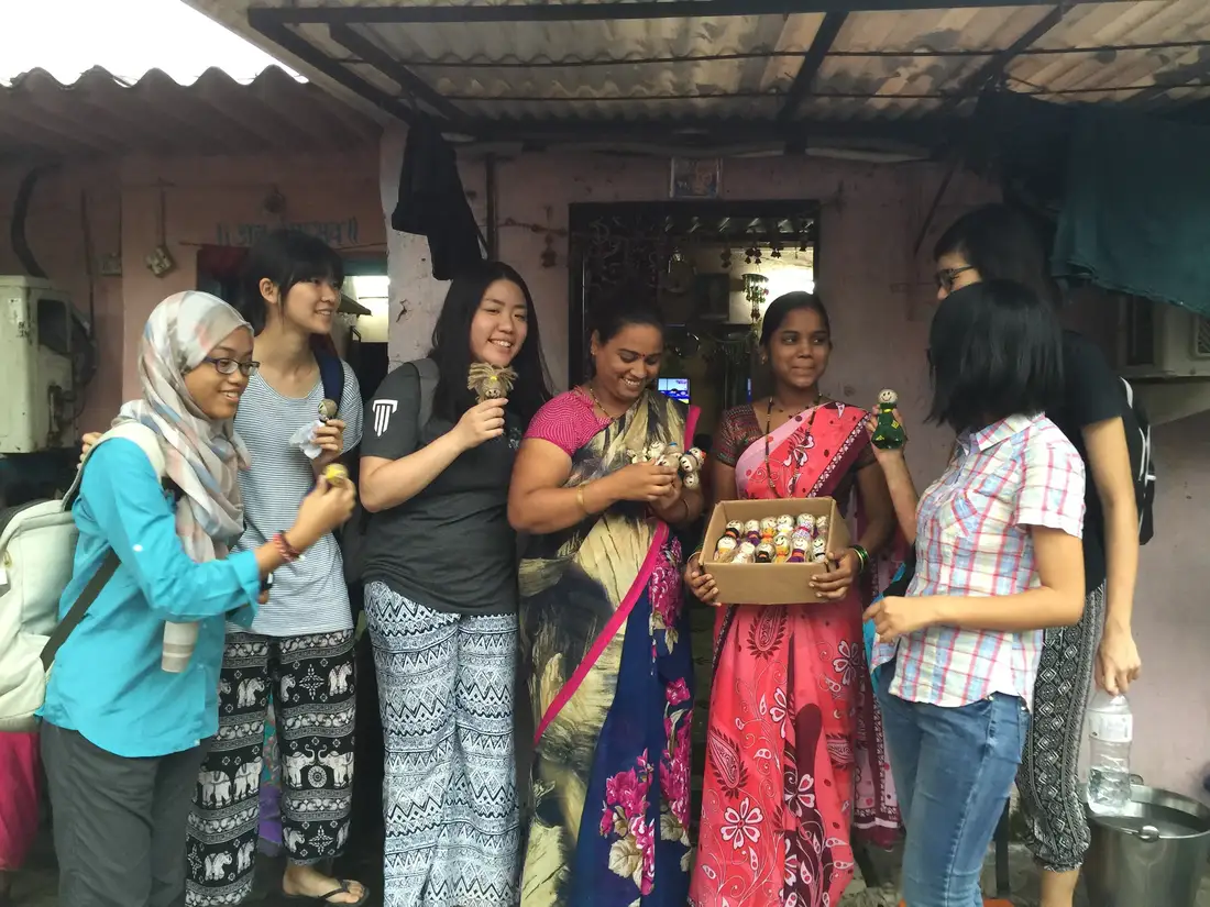 Women and international volunteers holding a box of handmade upcycled dolls, Earth5R CSR programme in Mumbai