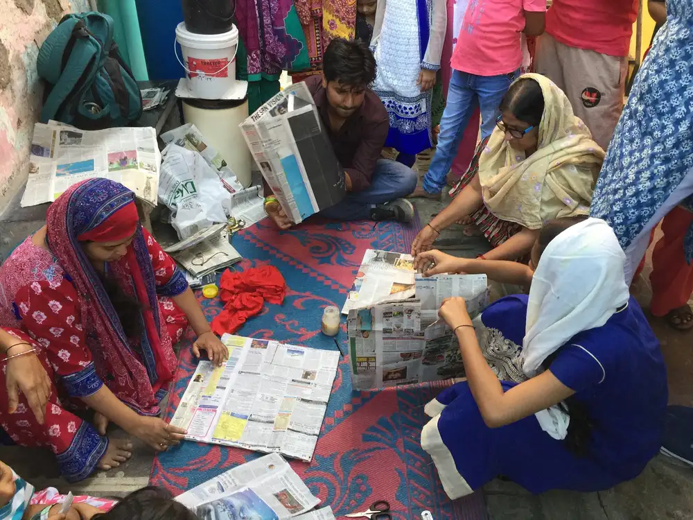 Women producing paper bags from newspaper together in their community, Earth5R CSR programme