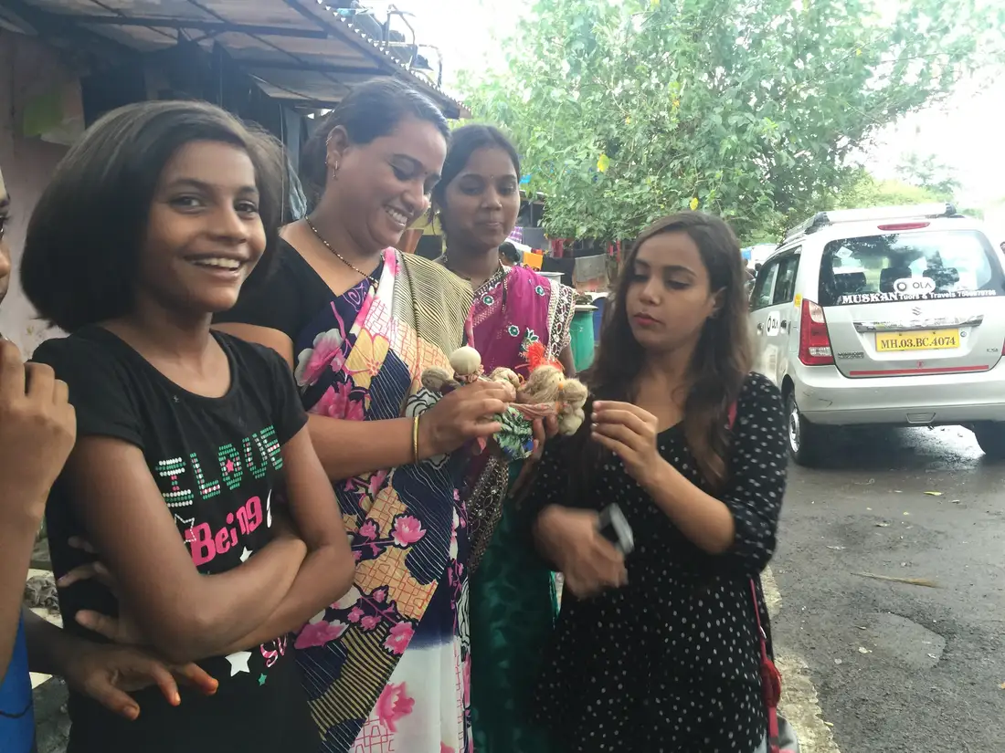 Local women and a girl showing handmade upcycled fabric dolls, Earth5R CSR programme in Mumbai