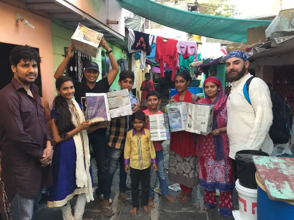 Women and Earth5R volunteers showing finished paper bags made from newspaper waste