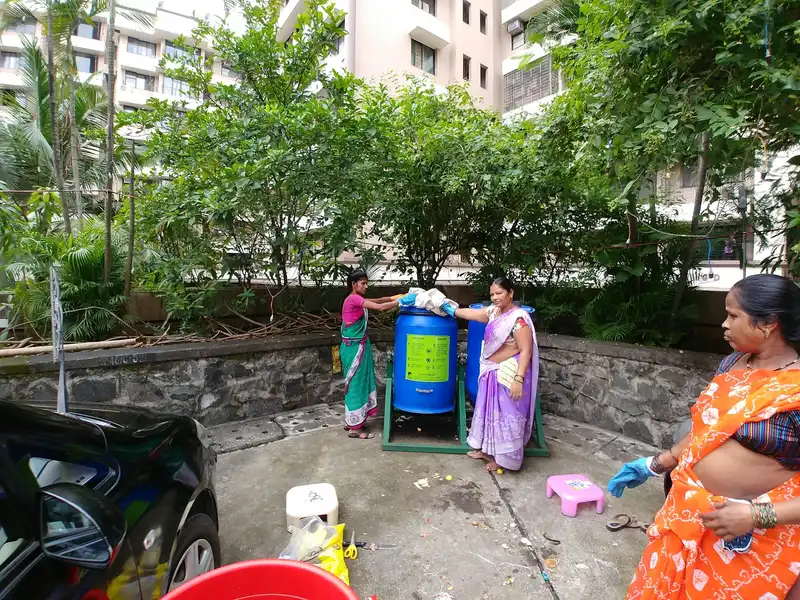 Biotechnology internship field work. Housekeeping staff adding wet waste to an Earth5R upcycled drum composter in a housing society